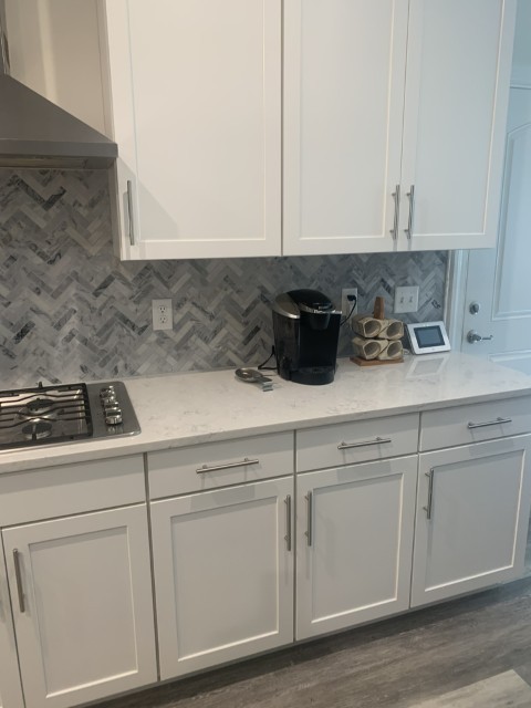 White shaker kitchen remodel with quartz countertops and herringbone backsplash