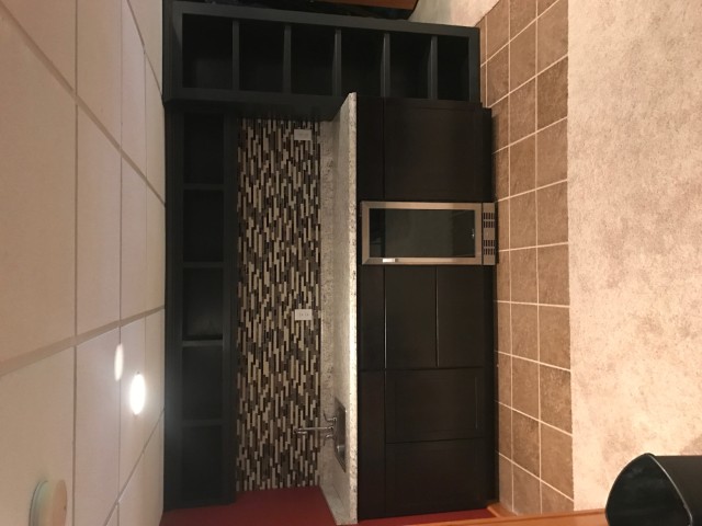 Custom espresso built-in bar with open cubbies and glass tile backsplash