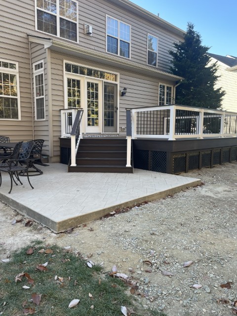 Composite deck with white vinyl railing and stamped concrete patio